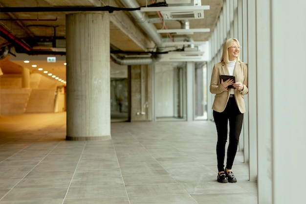 Businesswoman with digital tablet on modern office hallway