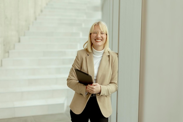 Businesswoman with digital tablet on modern office hallway