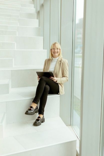 Businesswoman with digital tablet on modern office stairs