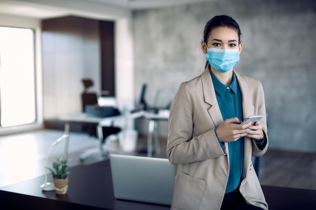 Businesswoman with face mas text messaging on cell phone in the office