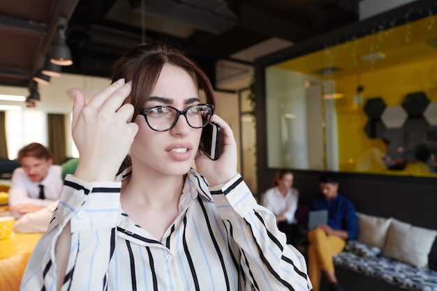 businesswoman with glasses using mobile phone at modern startup open plan office interior