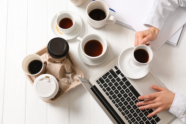 Photo businesswoman with a lot of empty cups of coffee working at table. concept of addiction