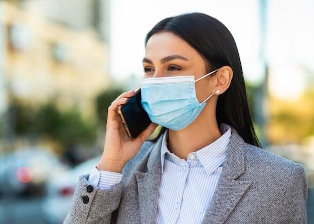 Businesswoman with medical mask talking on the phone