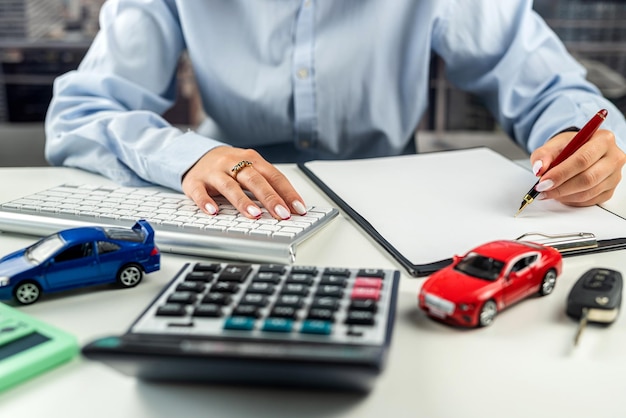 Businesswoman working on documents with small cars calculators and keys on the table