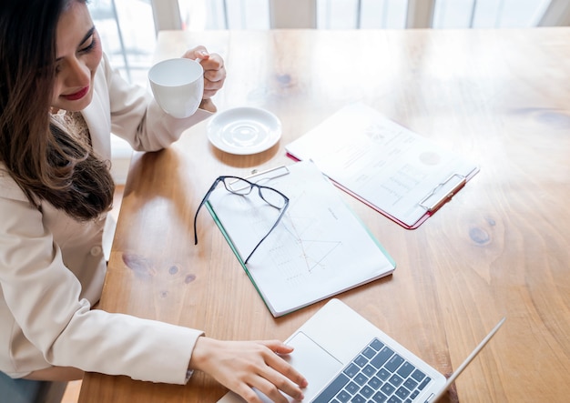 Businesswoman working at her office desk with document paper and laptop