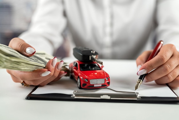 Businesswoman working on insurance documents with a small car on the table Auto and life insurance Dollars on the table