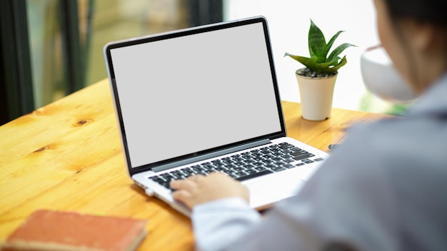 Businesswoman working on laptop computer at her desk, laptop blank white screen mockup for montage your graphic.