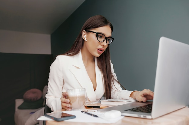 Businesswoman working on laptop computer sitting at home managing her business via home office during Coronavirus or Covid-19 quarantine