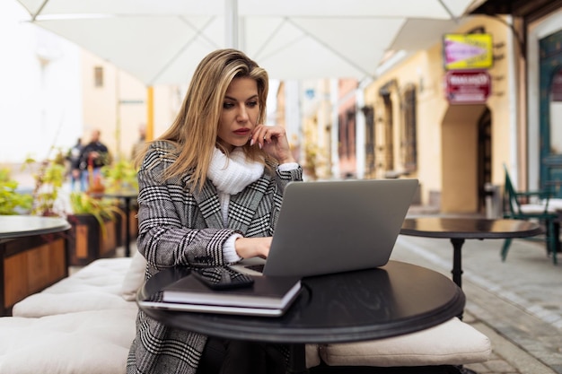 Businesswoman working on a laptop outside the office peering closely at the screen investment