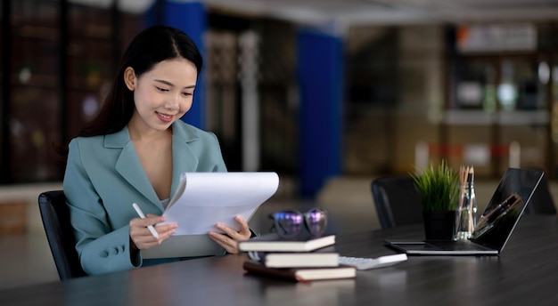 Businesswoman working with laptop computer and looking information on digital tablet.