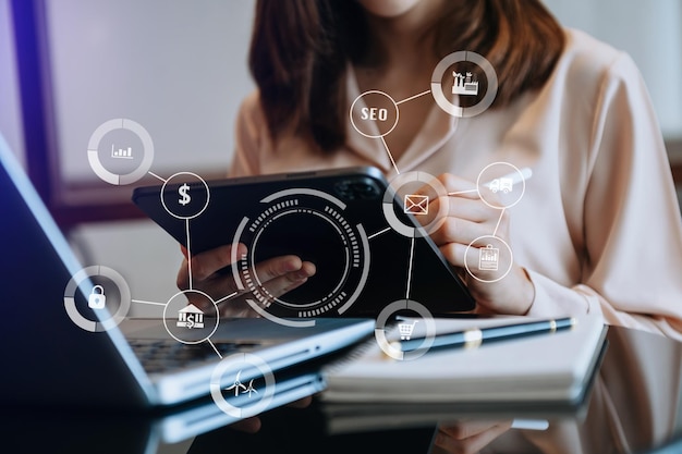 Businesswoman working with mobile phone and tablet and laptop computer Internet with Augmented Reality on VR dashboard on desk in modern office