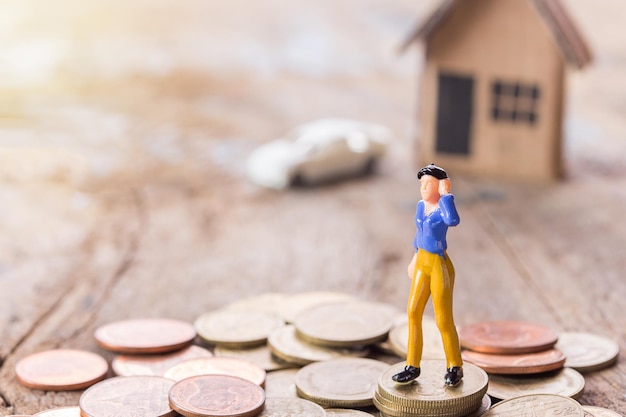 Businesswomen figures standing on the coin with blurred car and home background