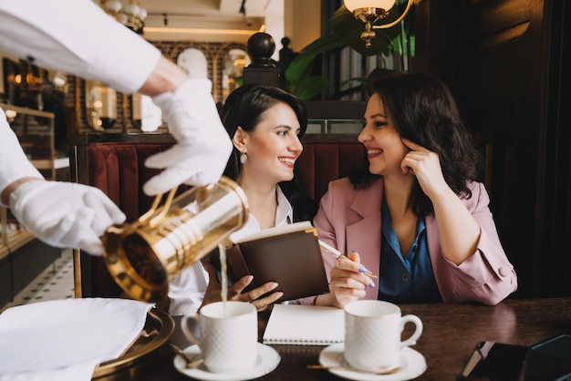 Businesswomen sit in a cafe drink coffee and have a business conversation discuss business and have fun