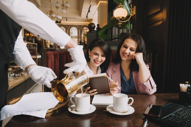 Businesswomen sit in a cafe drink coffee and have a business conversation discuss business and have fun