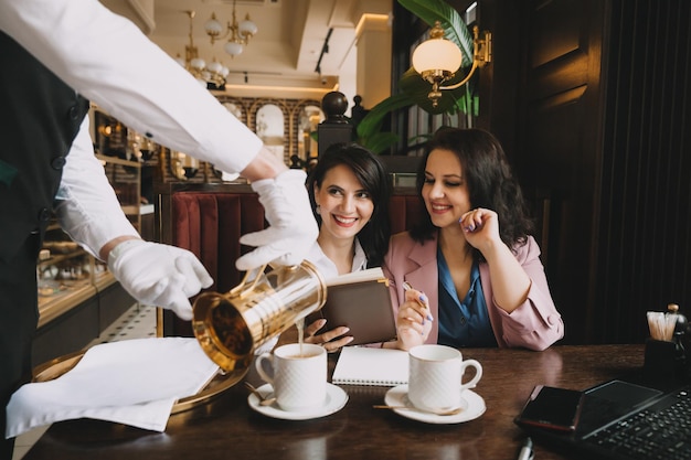 Businesswomen sit in a cafe drink coffee and have a business conversation discuss business and have fun