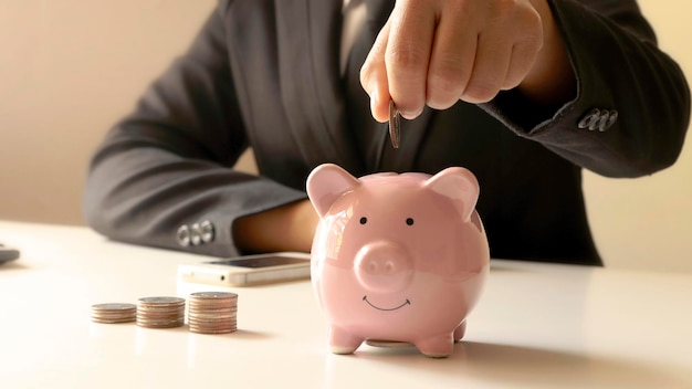 Businesswomen who hold coins in a piggy bank closely including pressing a calculator for moneysaving ideas