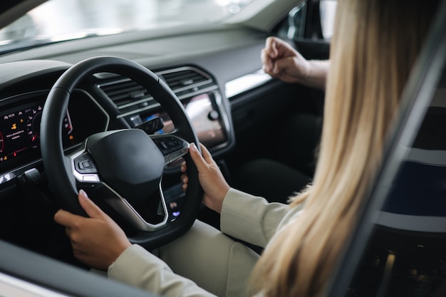 Bussines woman choosing car i car showroom salesperson sitting in car with customer and show desing