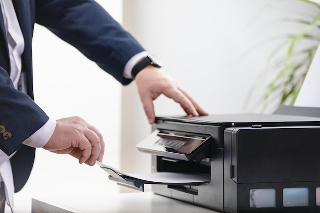 Bussinessman takes paper from printer scanner or laser copy machine in office