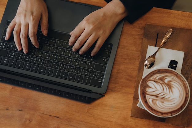 Busy asian woman drinking coffee while working on laptop outdoors