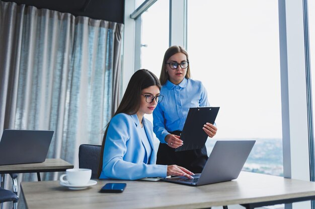 Busy business women with a laptop in the office watching content on the laptop and discussing the project together sitting in the office during a working break Teamwork corporate discussion