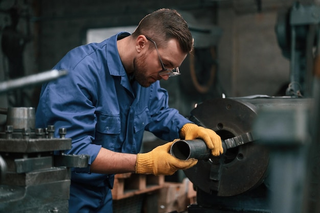 Photo busy by working with automatic machine man at factory and in blue uniform is indoors