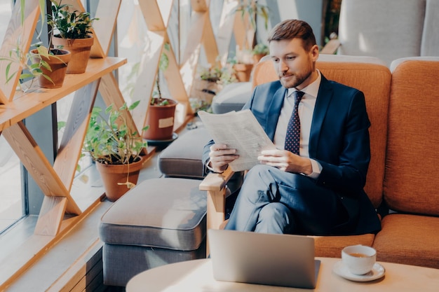 Busy corporate employee reading newspaper in cafe