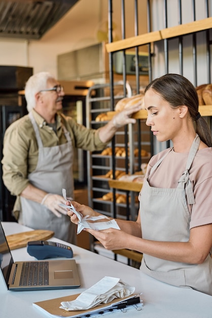 Busy female worker of bakery looking through receits