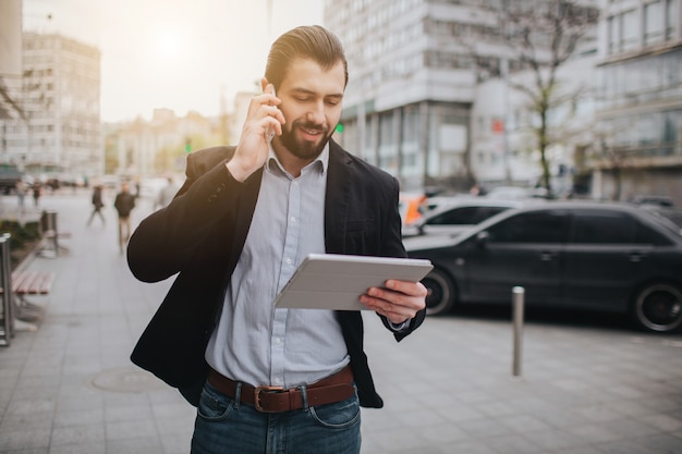 Busy man is in a hurry, he does not have time, he is going to talk on the phone on the go. Businessman doing multiple tasks. Multitasking business person.