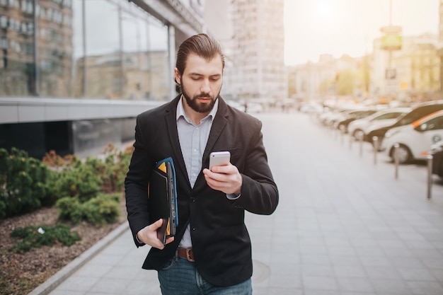 Busy man is in a hurry, he does not have time, he is going to talk on the phone on the go. Businessman doing multiple tasks. Multitasking business person.