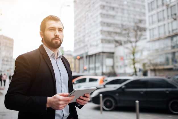 Busy man is in a hurry, he does not have time, he is going to use tablet pc on the go. Businessman doing multiple tasks. Multitasking business person.