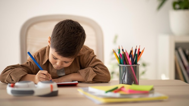 Busy serious european small kid drawing writing studying at table in living room