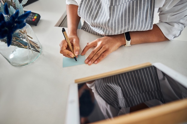 Busy shop assistant writing a quick paper note