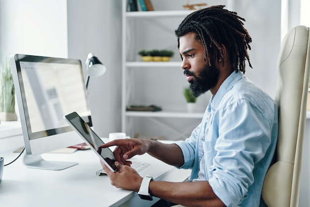 Busy young man using digital tablet while working in the office