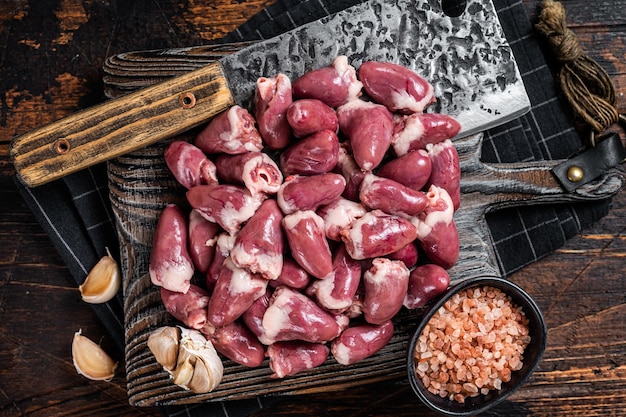 Butcher board with raw chicken hearts Wooden background Top view