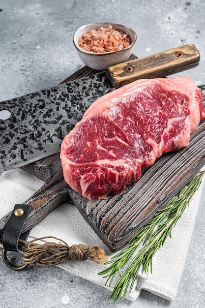 Butcher board with Raw striploin beef meat steak on wooden cutting board Gray background Top view