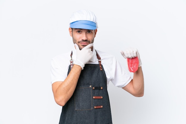 Butcher caucasian man wearing an apron and serving fresh cut meat over isolated white background thinking