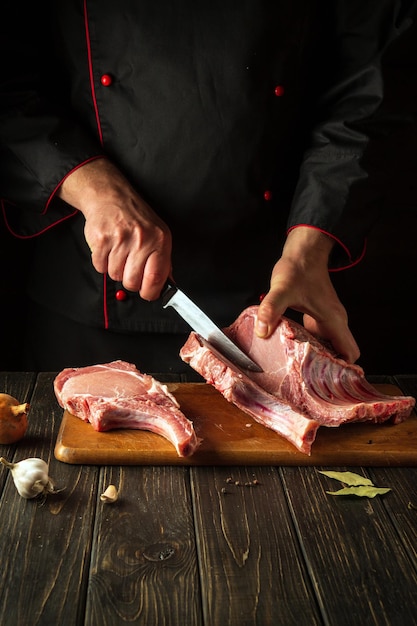 A butcher cuts raw ribs on a cutting board before preparing a meat dish European cuisine