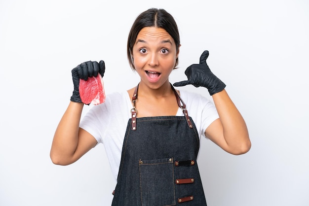 Butcher hispanic woman wearing an apron and serving fresh cut meat isolated on white background making phone gesture Call me back sign