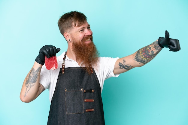 Butcher man wearing an apron and serving fresh cut meat isolated on blue background giving a thumbs up gesture