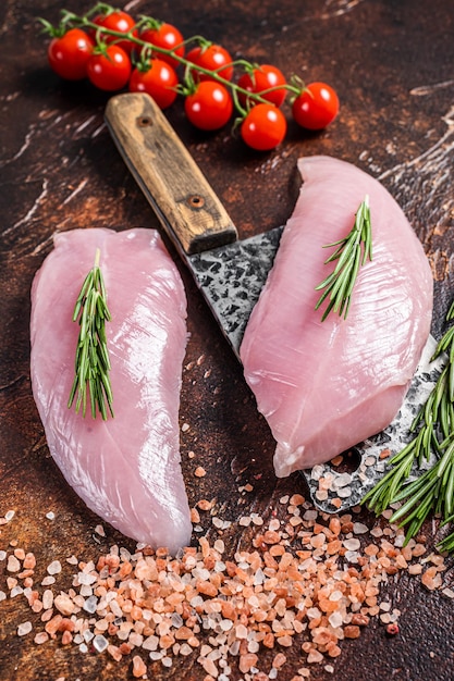 Butcher Raw Turkey steaks Breasts fillet on a meat cleaver Dark background Top view