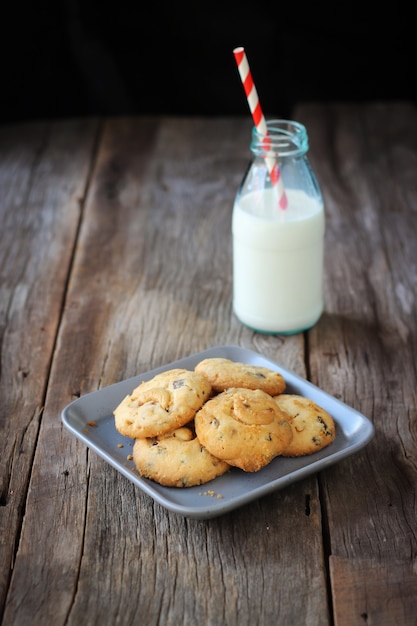 Butter cookies with Cashew nut and chocolate chip on plate served with bottle of milk. 