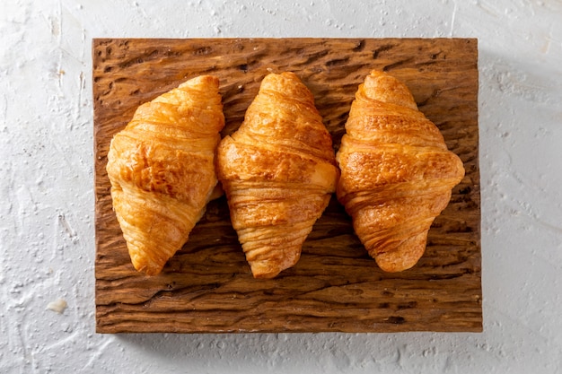 Butter croissants on a rustic wooden board.