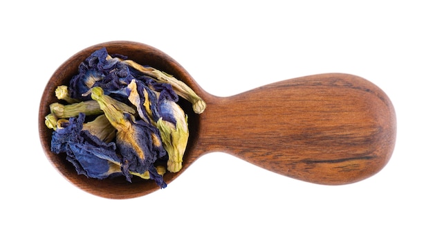 Butterfly pea flowers in wooden spoon isolated on white background Blue herbal tea Clitoria Ternatea Top view