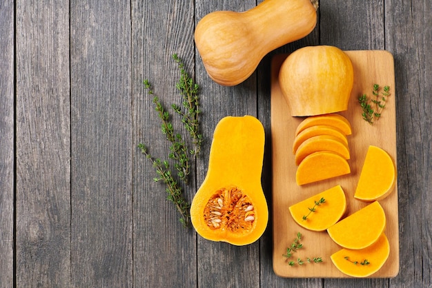 Butternut squash slices with thyme on a wooden table copy space for your text