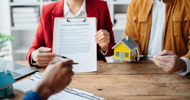 Photo buying a home or insurance deal an insurance agent pointing a pen to those interested in renting a house a contract signing an home buying agreement in officexa