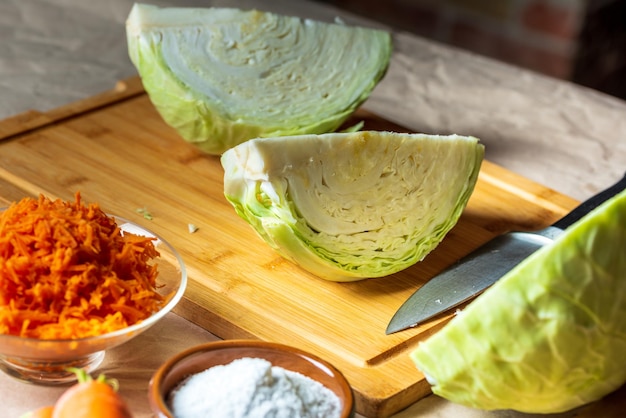 Cabbage on a cutting board carrot and knife next to it