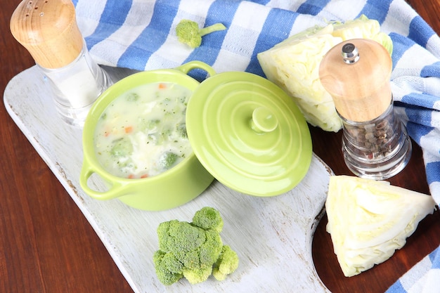 Cabbage soup in plate on board for cutting near napkin on wooden table