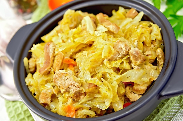 Cabbage stew with meat in black brazier on green napkin