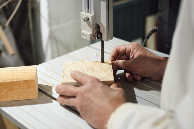 Cabinetmaker cutting piece of wood with electric saw