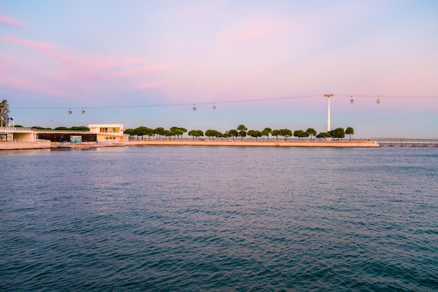 Cable cars overlooks the Vasco da Gama bridge on the Tagus river in Lisbon, Portugal during sunset